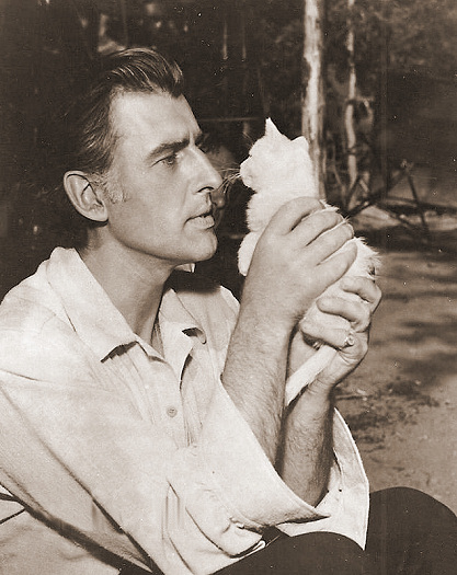 Stewart Granger holds aloft a white kitten