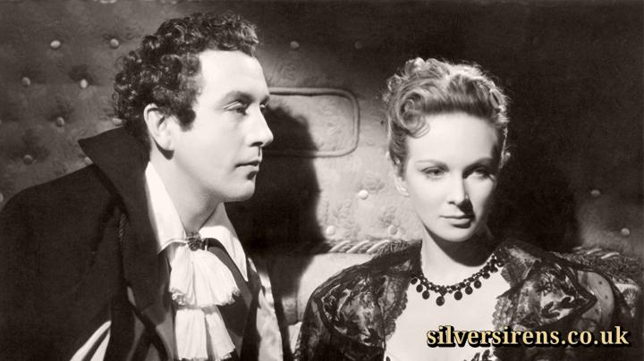 Lady Caroline Lamb (Joan Greenwood) turns away from Lord Byron (Dennis Price) in The Bad Lord Byron (1948).  The couple are seated 
in a 19th century padded coach.