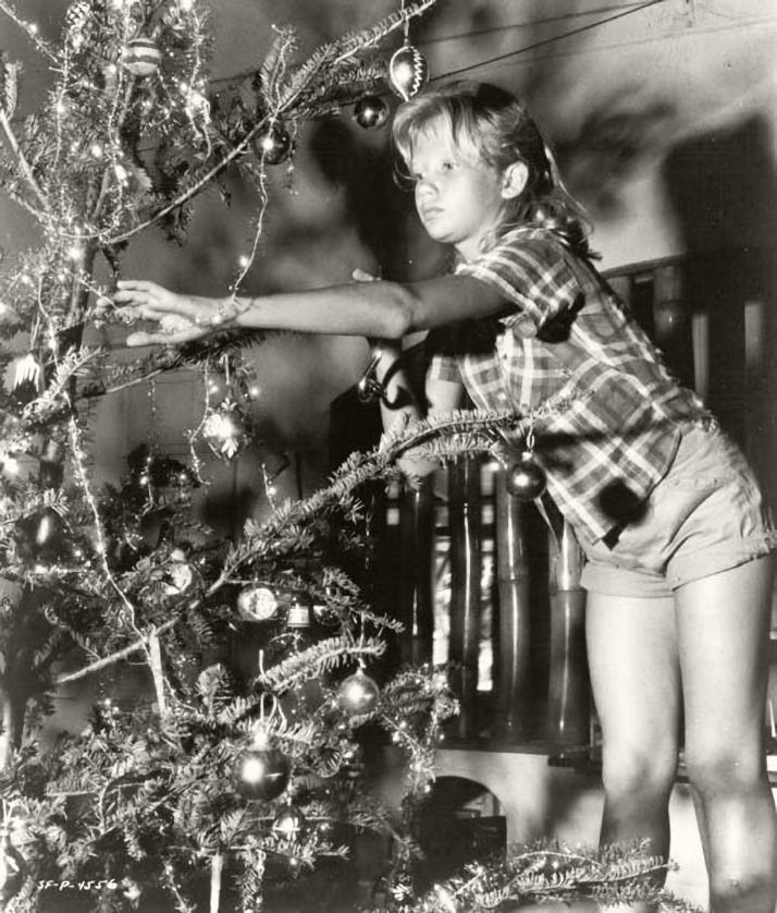 Photograph of Hayley Mills, British actress as a child, reaching over to decorate her Christmas tree