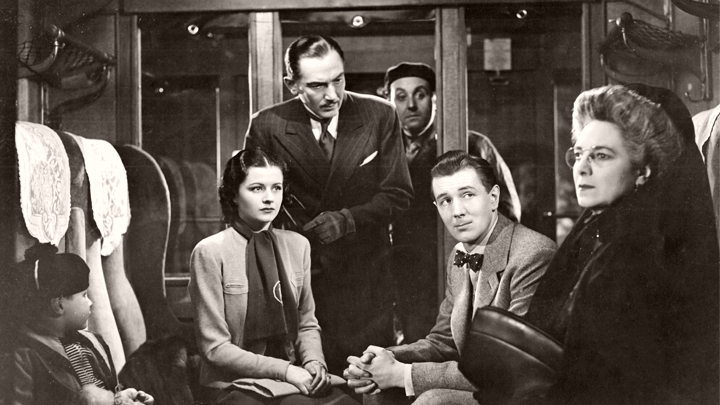 In the train carriage, Dr Hartz (Paul Lucas) questions Signora Doppo (Zelma Vas Dias) as Iris (Margaret Lockwood) and Gilbert (Michael Redgrave) look on