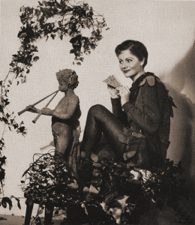 Publicity photograph for Peter Pan at the Scala Theatre in 1949.  Margaret Lockwood holds a traditional panpipe while she observes a statue of the God pan, who is depicted playing a long, double flute 
