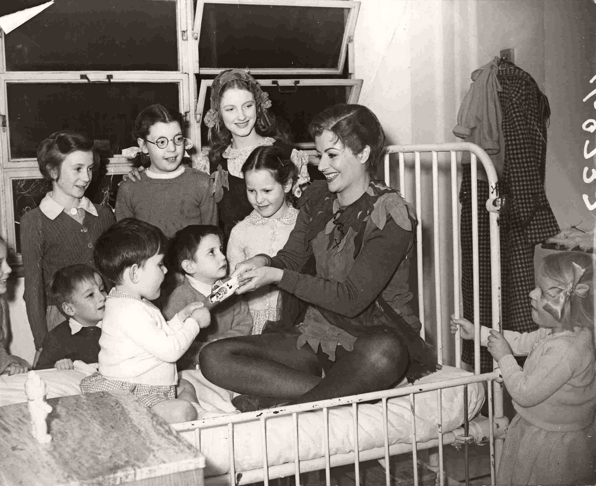 Margaret Lockwood, in costume as Peter Pan, perches on a bed in the ward and laughs as she pulls a Christmas cracker and plays with the children at London’s Great Ormond Street Hospital in 1949