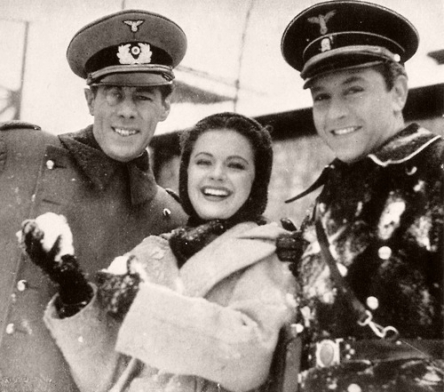 Margaret Lockwood plays with a snowball during a break from filming Night Train to Munich. Rex Harrison and Paul Henreid look on.