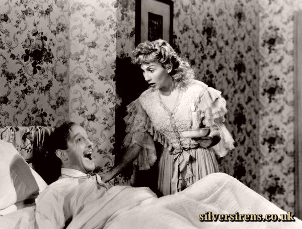 Roland Culver (Richard Halton) sits up in bed in On Approval as Googie Withers (Helen Hale) looks on 