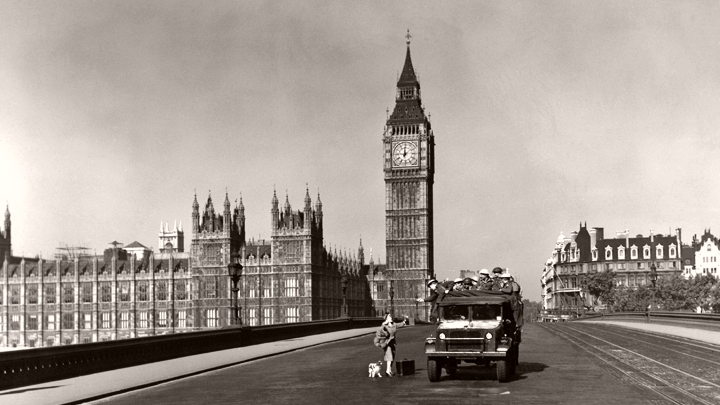 A deserted Westminster bridge and Big Ben form the background as an army truck stops a woman and her dog out during curfew.  A scene from Seven Days to Noon (1950)