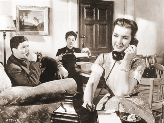 Captain Wilding (Anthony Steel) looks on as his wife Anne (Patricia Roc) takes another phone call as her secretarial business goes from strength to strength
